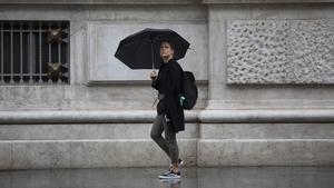 Una mujer se protege de la lluvia con su paraguas
