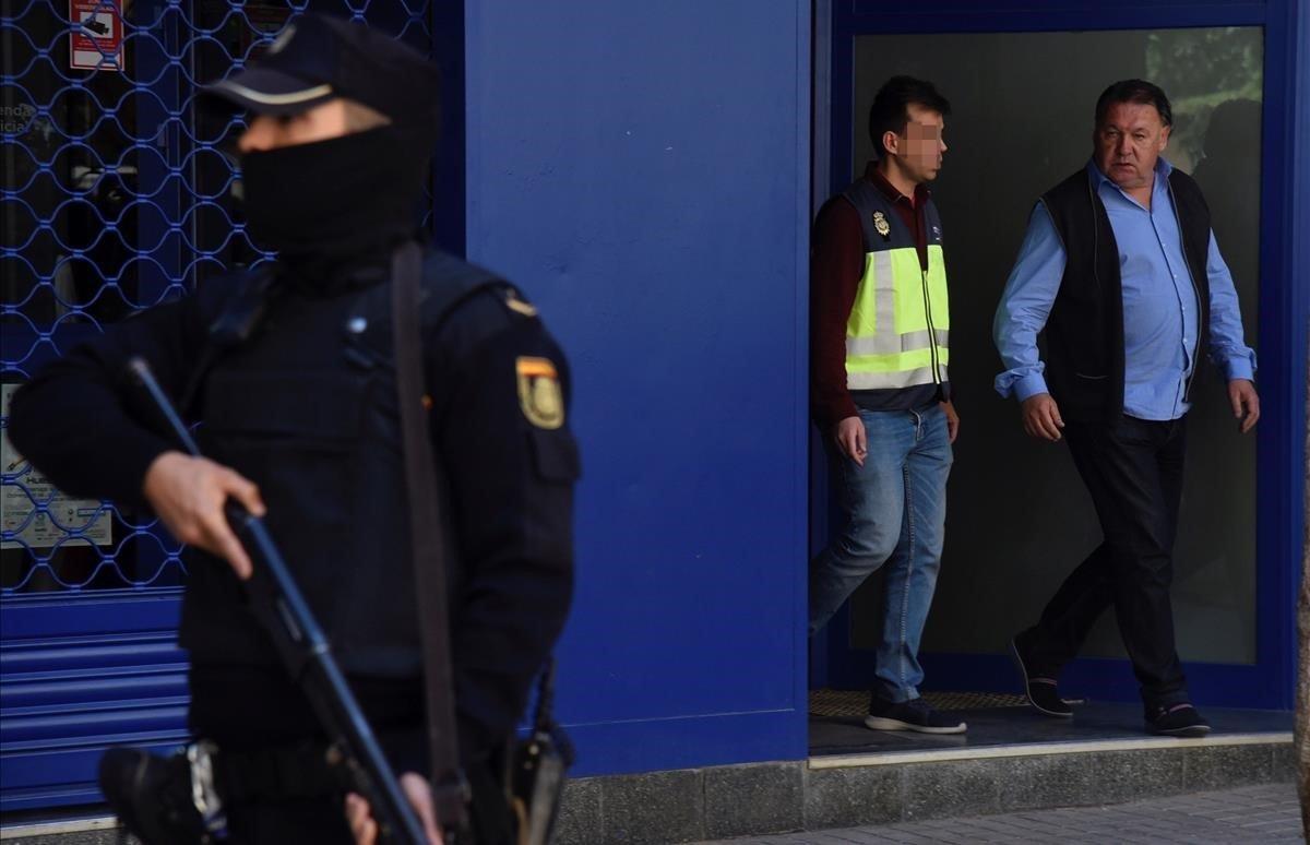 El presidente del Huesca, Agustín Lasaosa, junto a un policía a su salida de las oficinas del club tras ser detenido durante la Operación Oikos contra el presunto amaño de partidos de fútbol en Primera y Segunda División