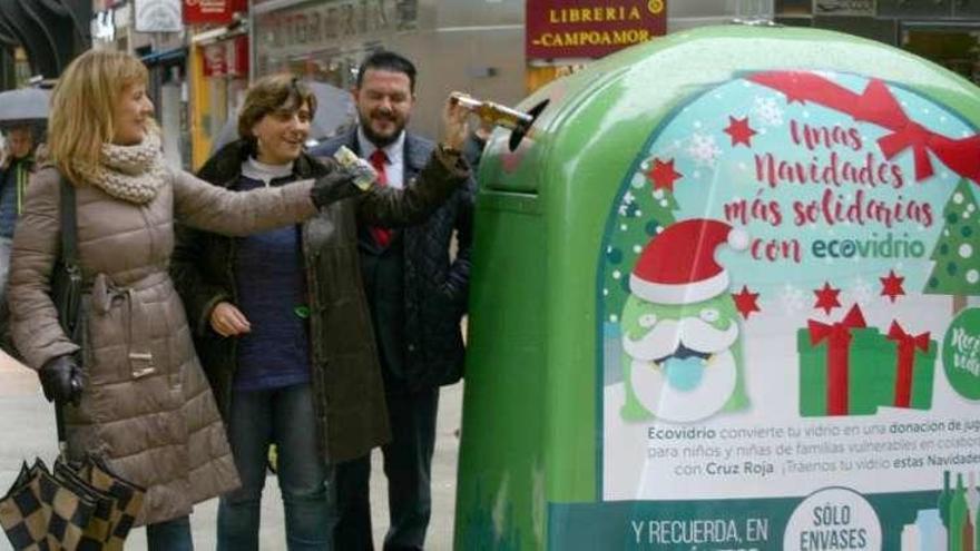 Las ediles Marisa Ponga y Ana Rivas meten vidrio en un contenedor.