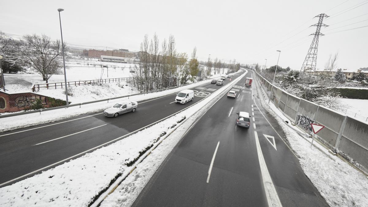 Varios coches circulan por una carretera con los laterales cubiertos de nieve, a 19 de enero de 2023, en Pamplona, Navarra (España). La Agencia Estatal de Meteorología (Aemet) mantiene la alerta naranja por acumulación de nieve en Navarra. Pamplona ha ama