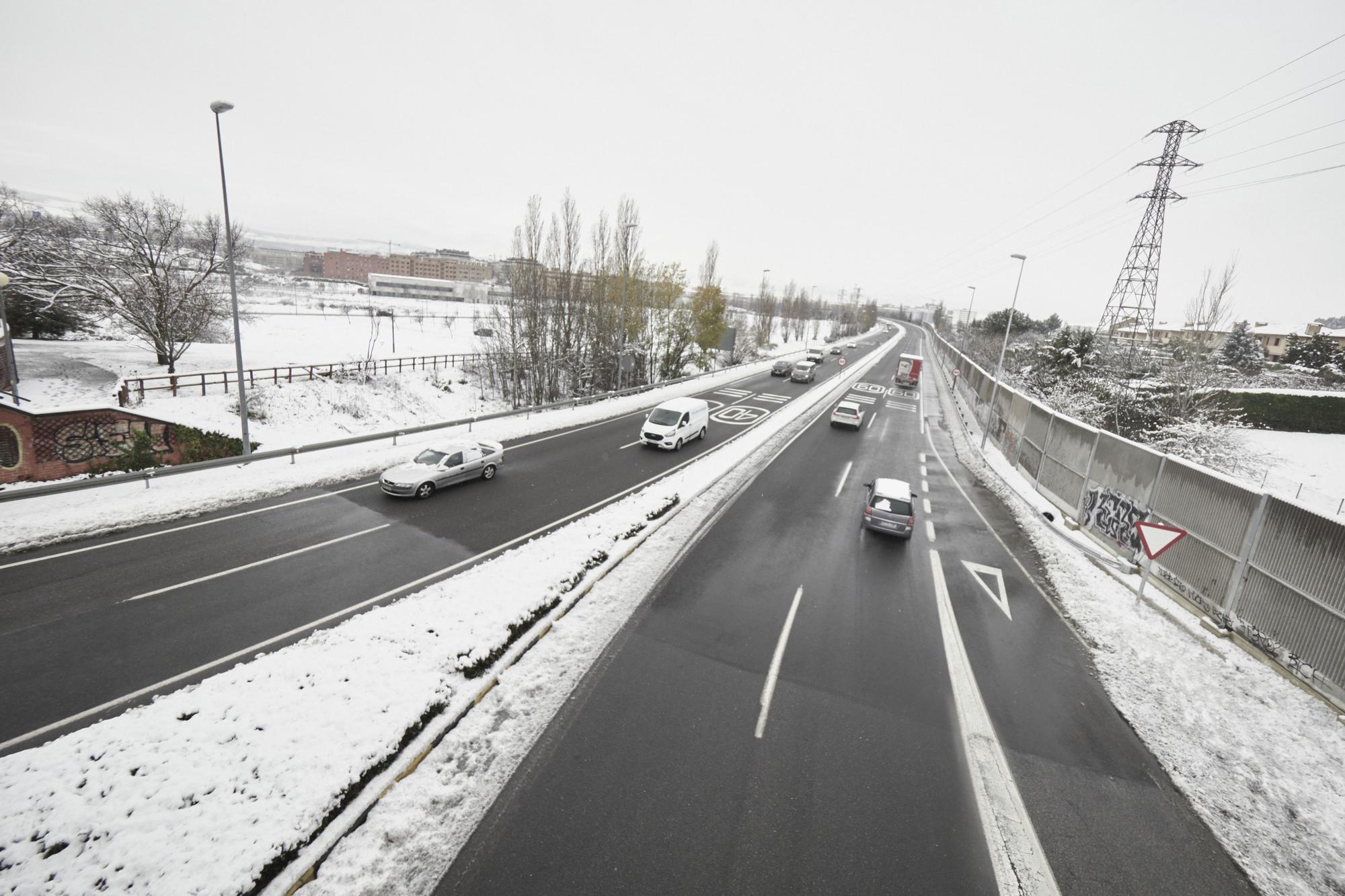 Varios coches circulan por una carretera con los laterales cubiertos de nieve, a 19 de enero de 2023, en Pamplona, Navarra (España). La Agencia Estatal de Meteorología (Aemet) mantiene la alerta naranja por acumulación de nieve en Navarra. Pamplona ha ama
