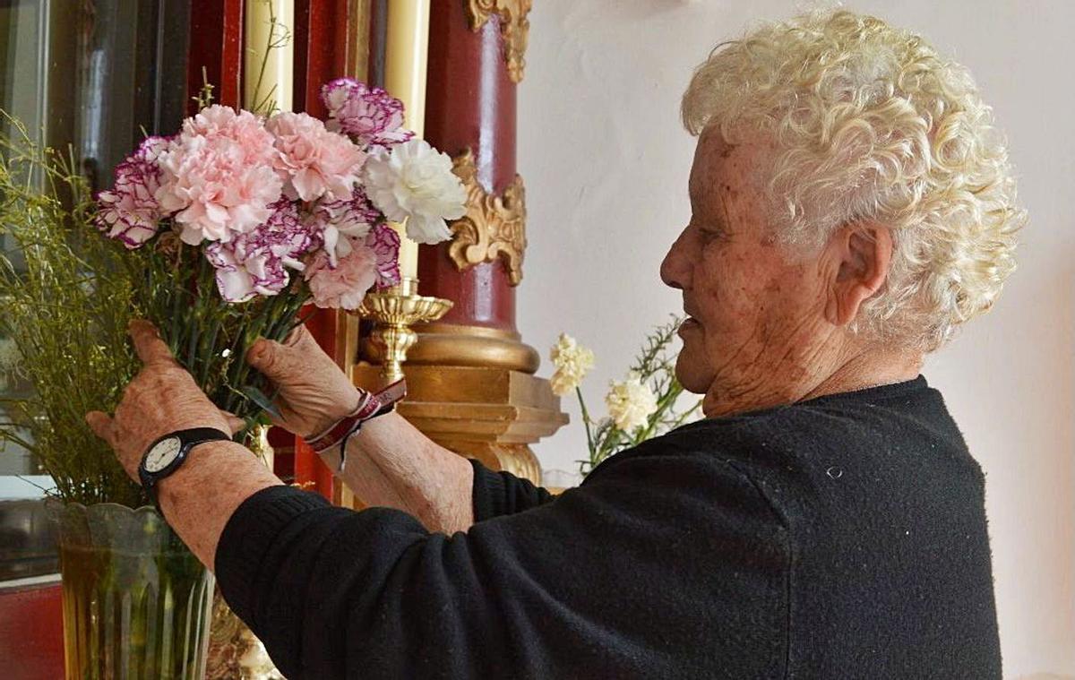 La guardesa arreglando las flores de la capilla. | ALBA ROSADO