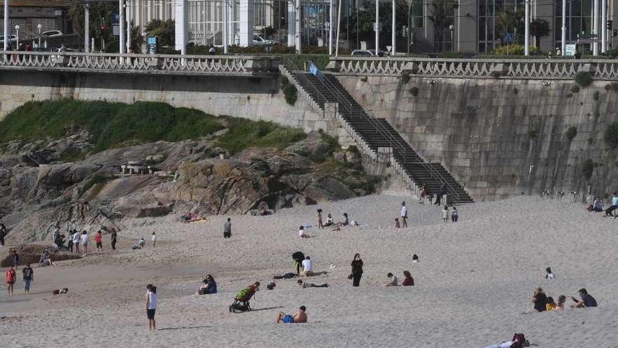 Varios grupos de personas al sol, ayer, en la coruñesa playa del Orzán.