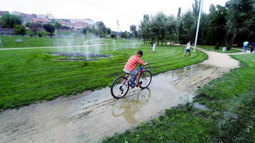 Un niño en bicicleta pasea entre el barrizal formado en el parque de Huerta de la Frontera.