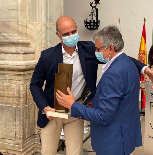 El alcalde entrega el premio al escritor.