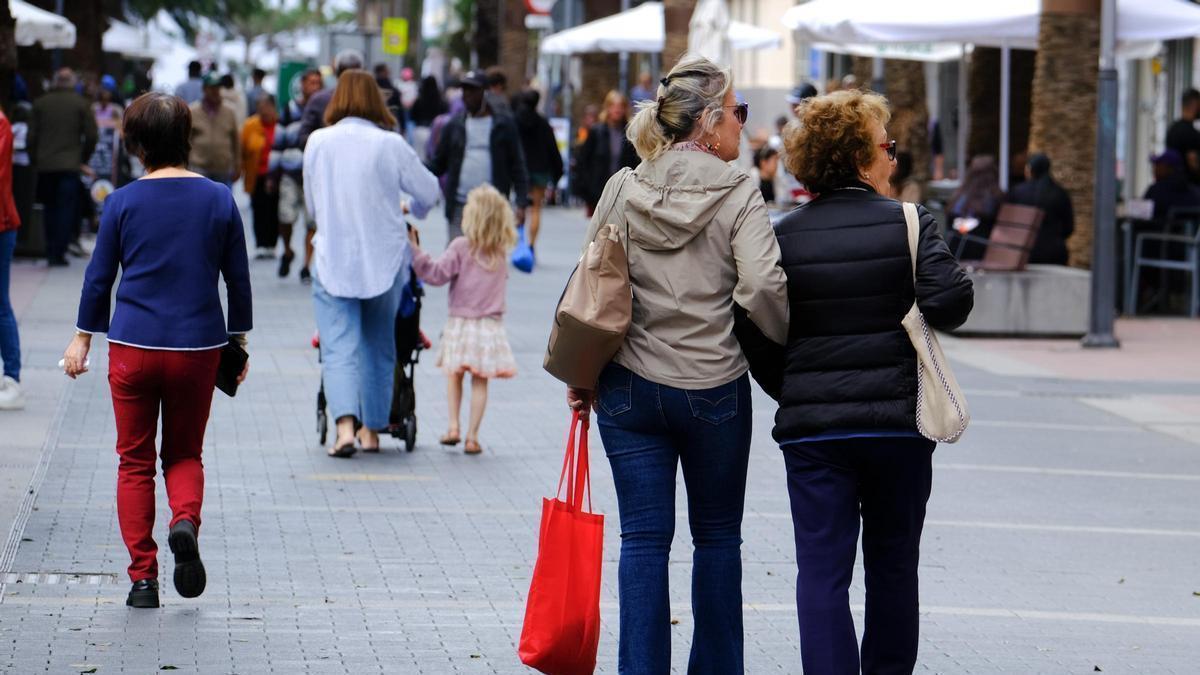 Varias personas pasean por una calle comercial.