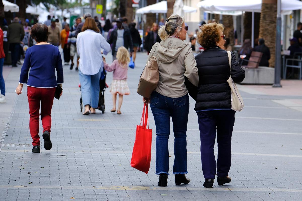 Varias personas pasean por una calle comercial.