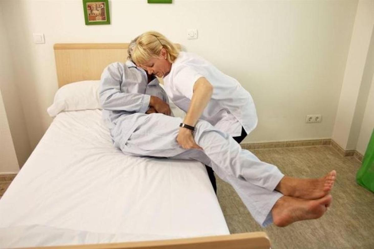 Una trabajadora de ayuda a domicilio atiende a una persona mayor.