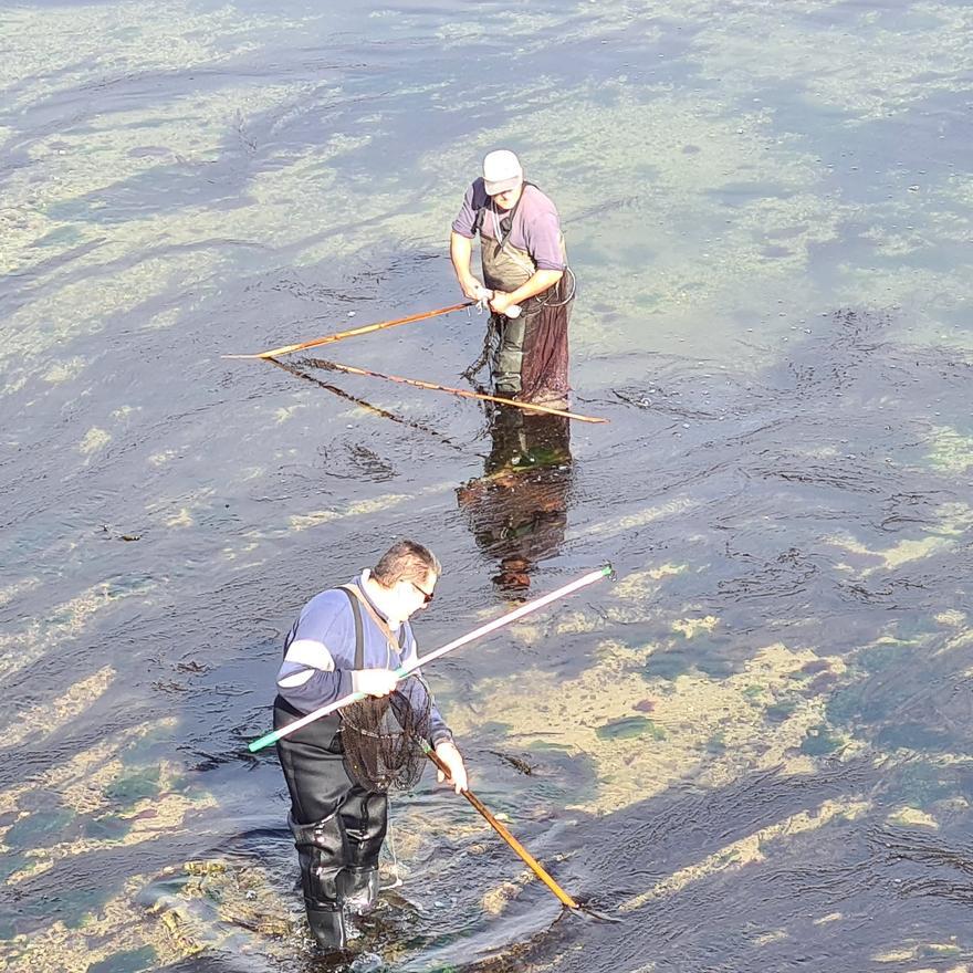 Dos pescadores, uno de ellos con un chopo en la mano.