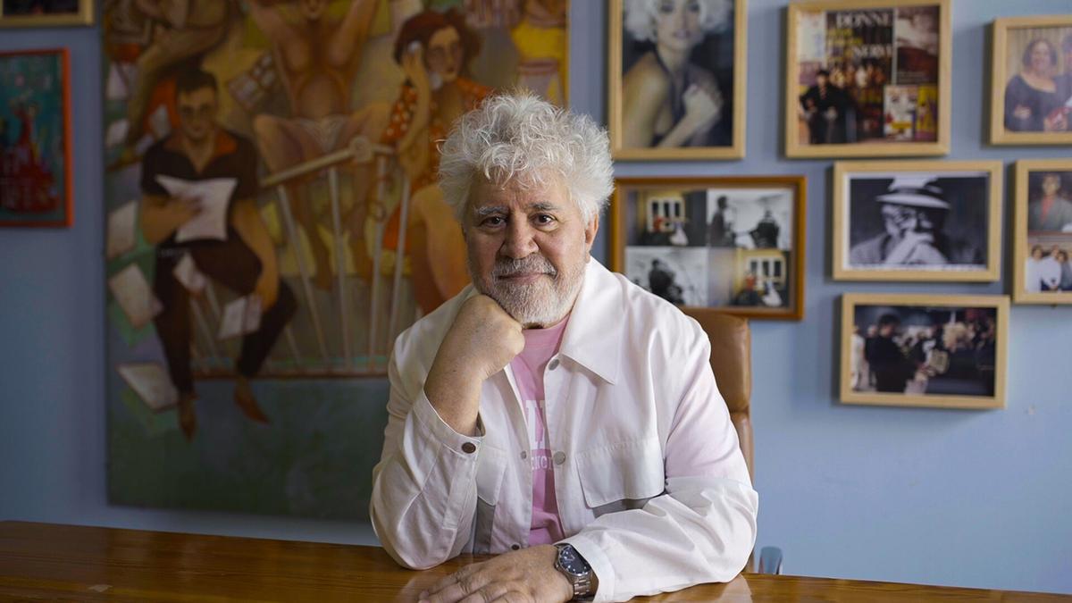 Pedro Almodóvar sentado con cuadros detrás.