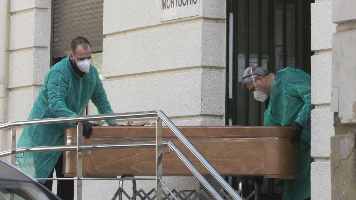 Dos operarios manejan un ataúd a la entrada del mortuorio del Hospital General. | FERNANDO BUSTAMANTE