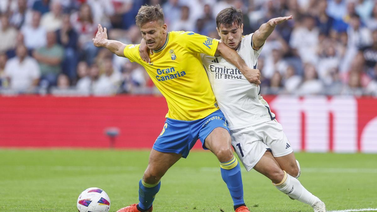 El centrocampista del Real Madrid, Brahim Díaz (d), pelea un balón con Eric Curbelo, de Las Palmas