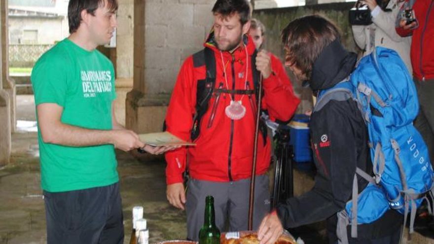 Javier Blanco, a la izquierda, saluda a dos peregrinos en el cabildo de Villapedre.