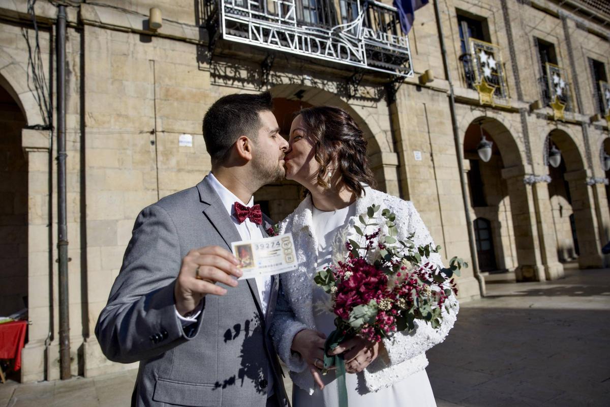 Adrián Tranche y Ana Martínez se dan un beso, con un décimo en la mano, delante del Ayuntamiento de Avilés