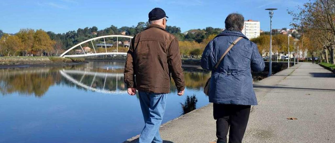 Una pareja de personas mayores pasea por la orilla del río Lérez. // Gustavo Santos