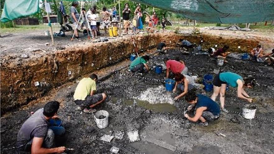 Els arqueòlegs excaven en el fang mil·lenari de la Draga sota la mirada dels primers visitants de les jornades de portes obertes.