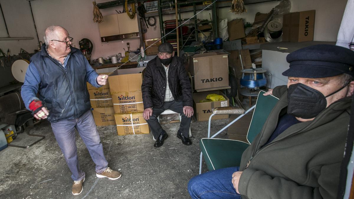 Un grupo de vecinos de Cudillero, charlando en una bodega del puerto, con curadillo secado y colgado en el interior.
