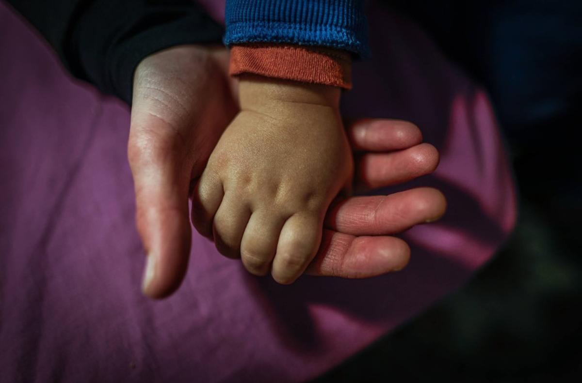 Una madre coge la mano de su bebé, en su casa de Barcelona.