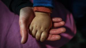 Una madre coge la mano de su bebé, en su casa de Barcelona.