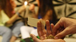 Un joven se prepara un porro de marihuana.