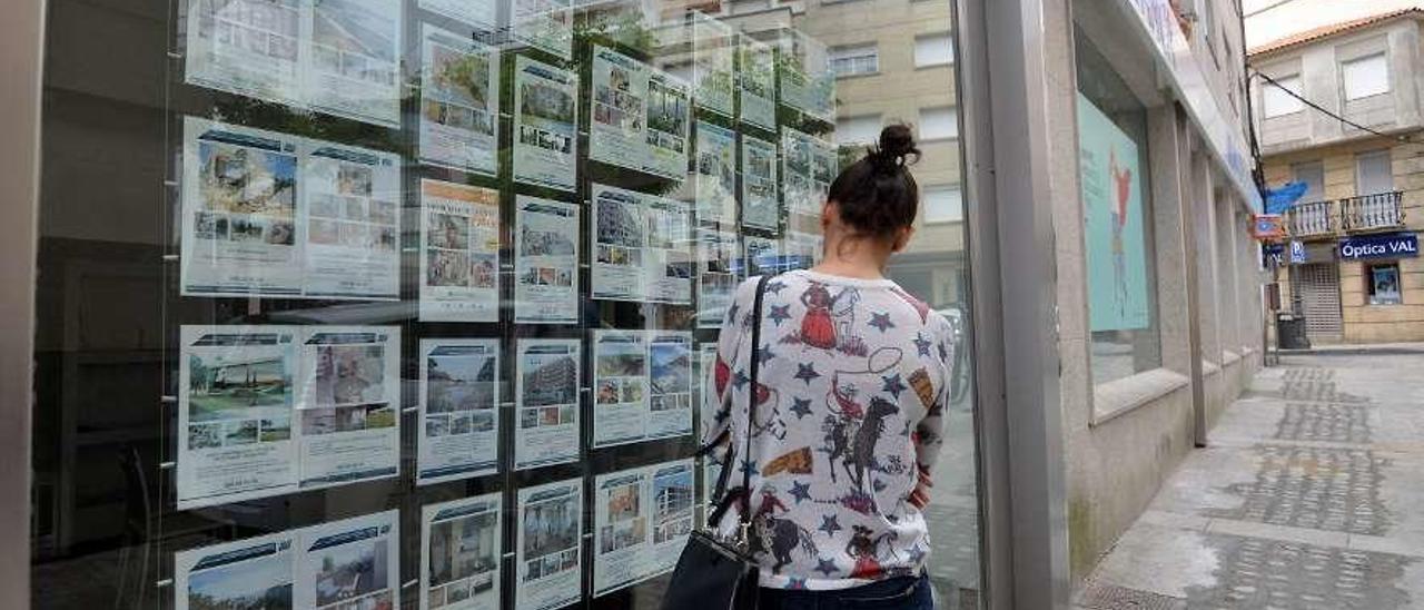 Una mujer leyendo, anuncios de alquiler y venta de pisos en Sanxenxo. // G. Santos