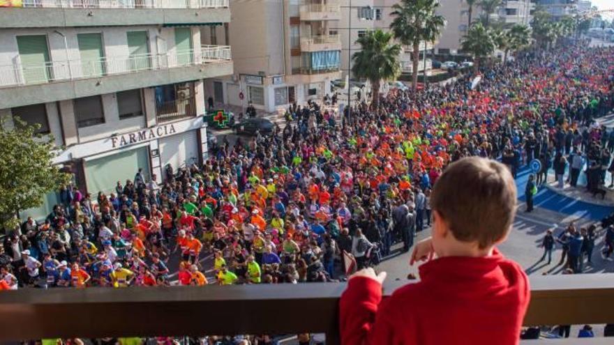 Un niño contempla desde un balcón de Santa Pola la multitud de corredores que tomaron la salida en enero de 2016 en la última edición de la Mitja Marató.