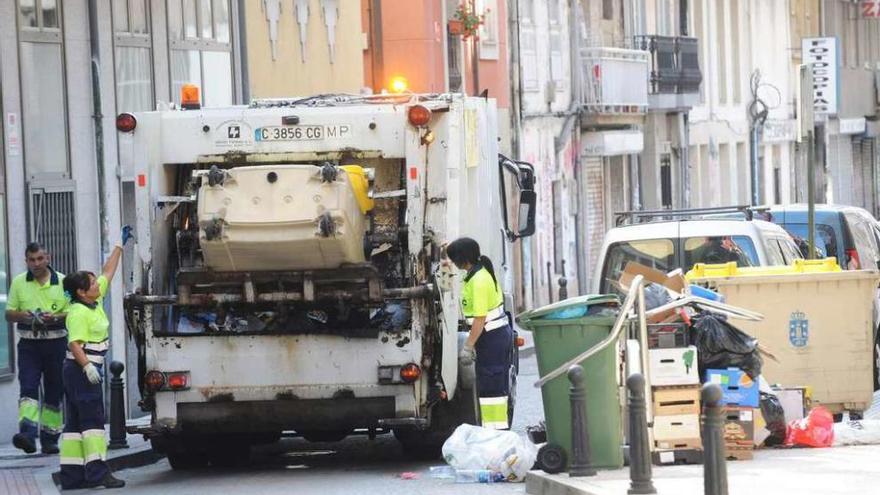 Un camión de la basura recoge un contenedor a pleno luz del día en una calle de la ciudad.