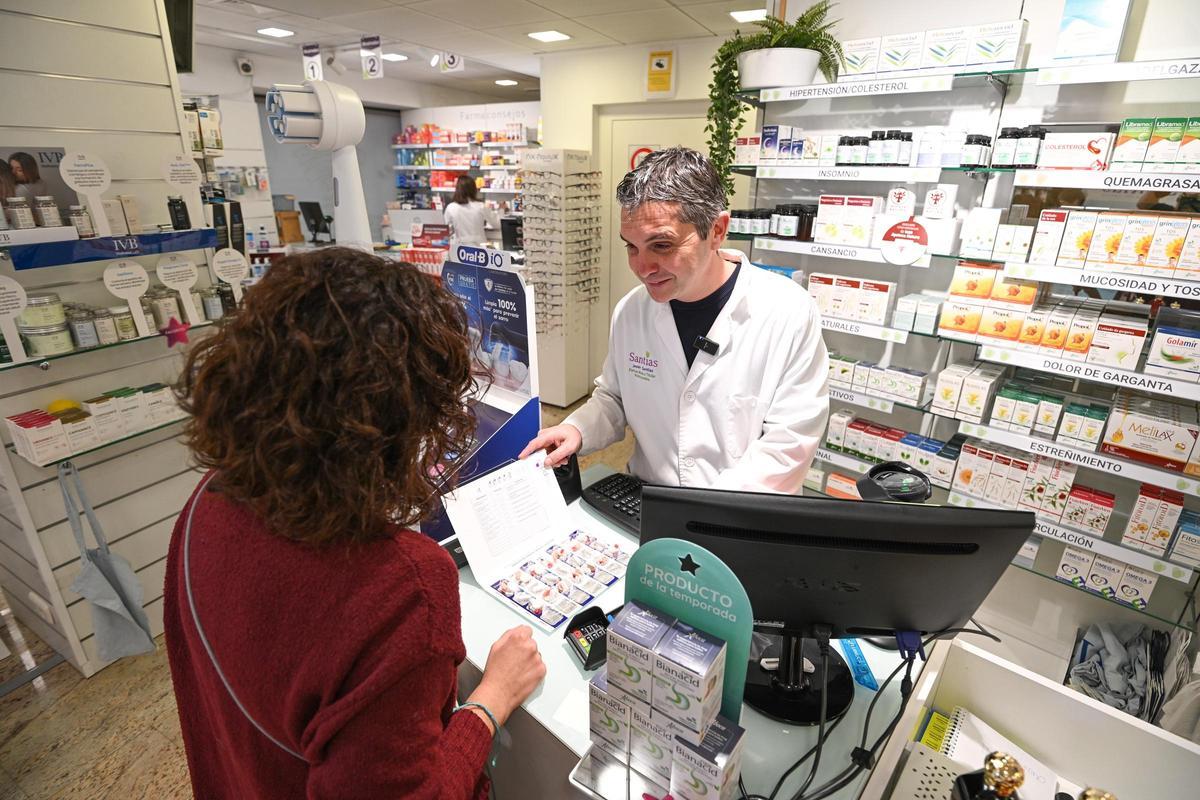 El farmacéutico Javier Santías en Aspe atiende a una clienta.