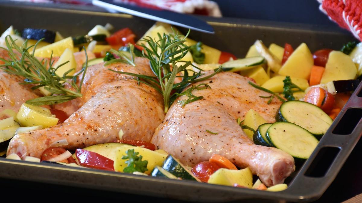 Una bandeja con pollo y verduras, lista para hornear.