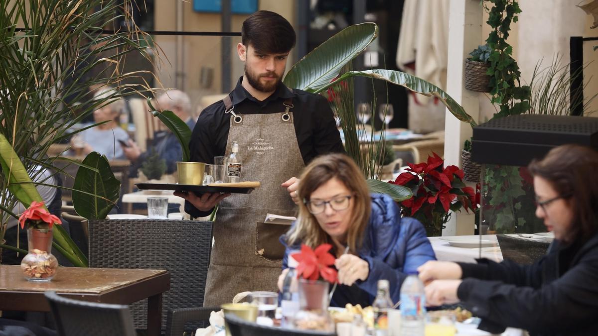 Un camarero atiende a unas clientas en un establacimiento de Málaga.