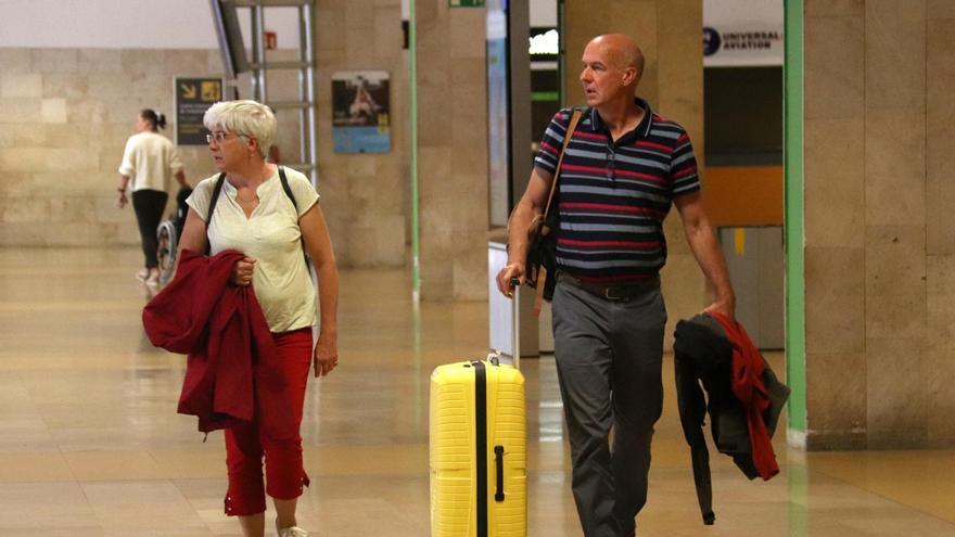Dos passatgers de l'aeroport de Girona passegen per la terminal amb l'equipatge.