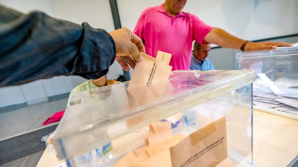 Un votante deposita su papeleta ante la mirada de los responsables de una mesa electoral.