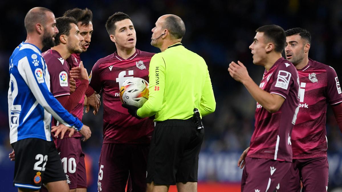 Los jugadores de la Real piden explicaciones a Mateu tras el gol anulado.