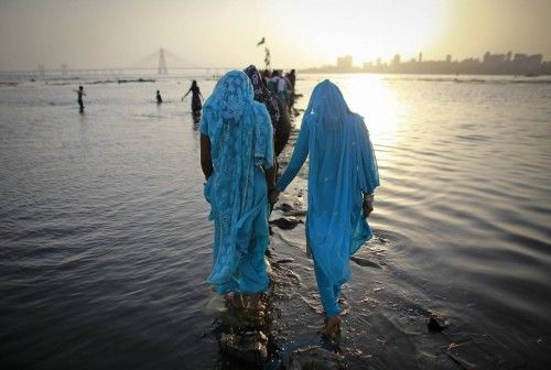 Devotos caminan por una senda de cemento en el mar Arábigo para orar en un santuario