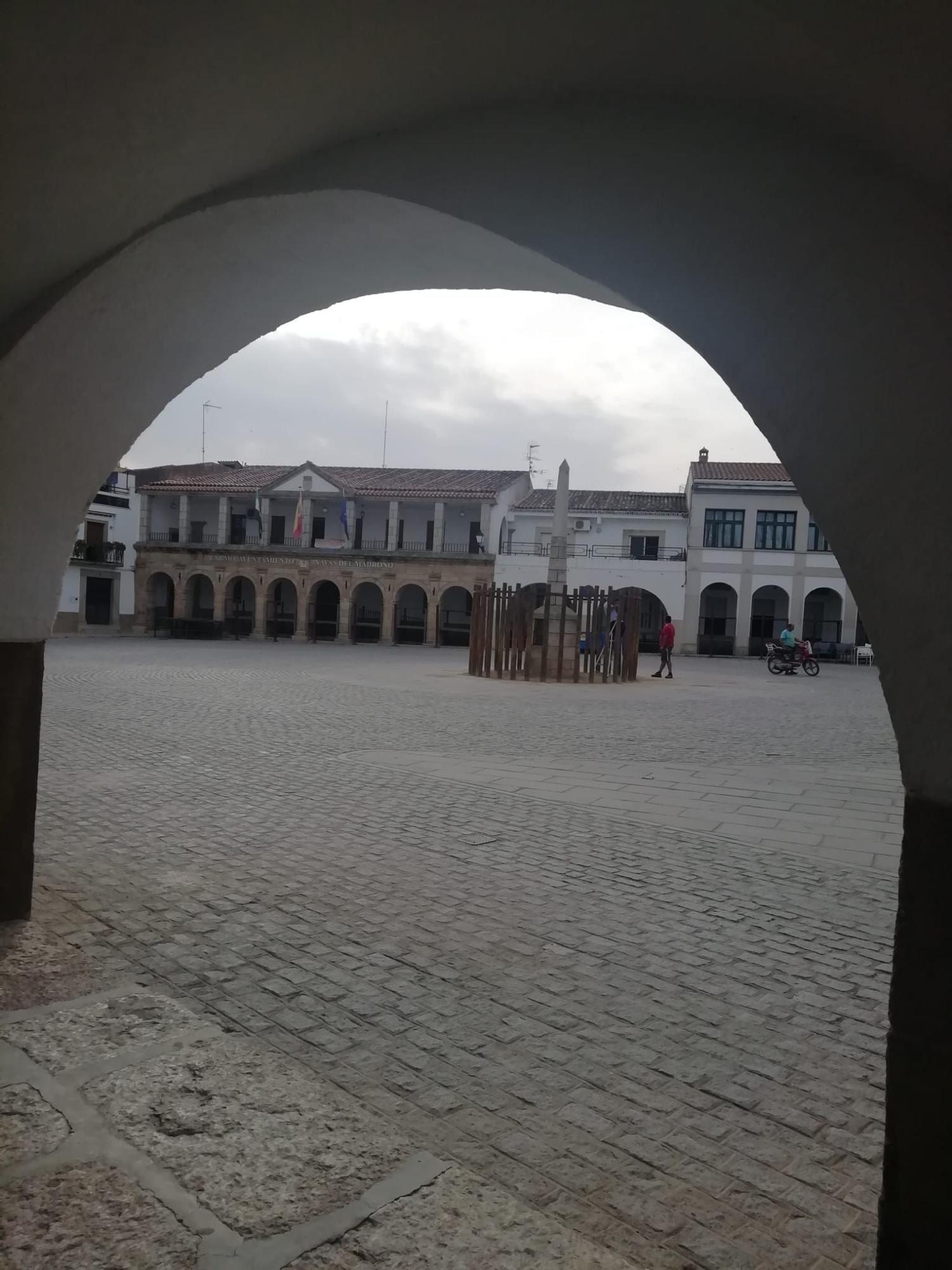 Vistas a la fachada del ayuntamiento de Navas del Madroño desde uno de los arcos de la plaza.