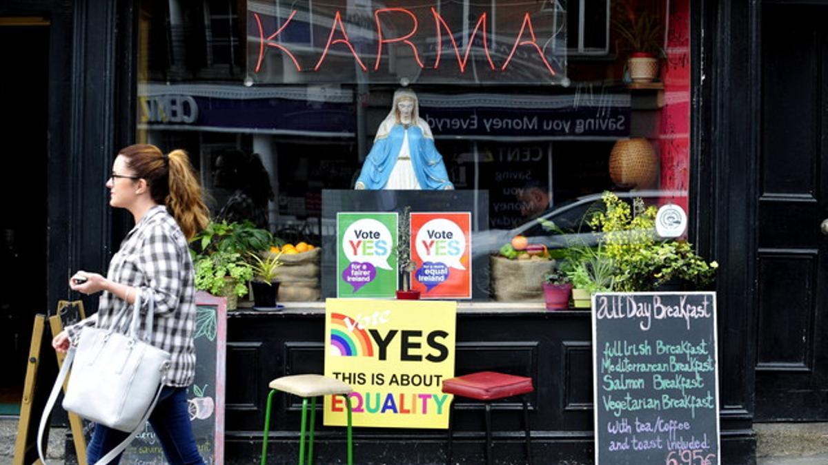 Una mujer camina junto a dos carteles sobre el referéndum para la legalización del matrimonio entre parejas del mismo sexo en Dublín