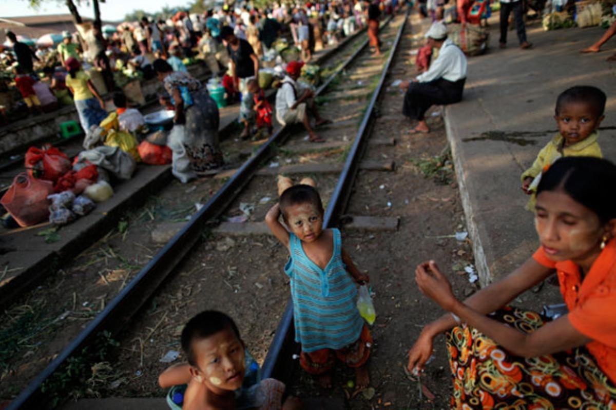 Desenes de venedors esperen un tren per anar al mercat on treballen en un barri de Rangun (Myanmar).