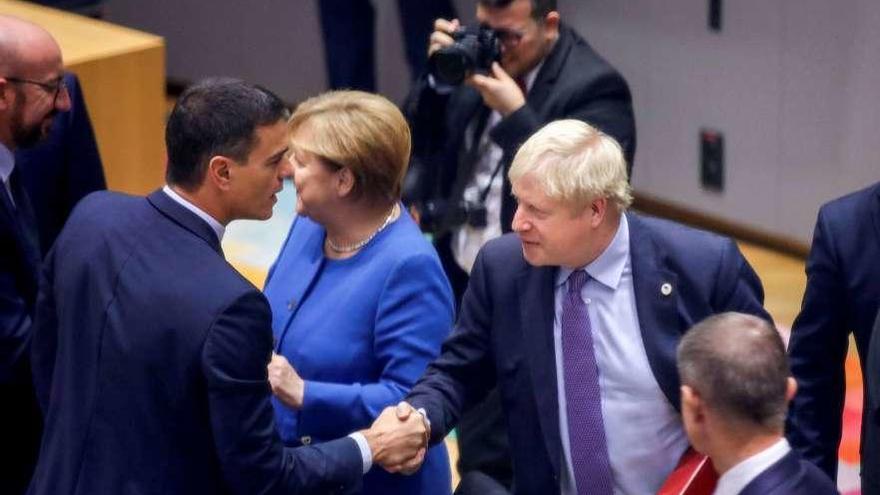 Pedro Sánchez saluda a Boris Johnson, en presencia de Angela Merkel. // Reuters