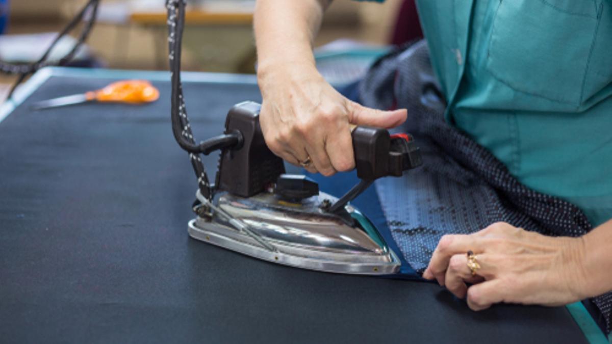 Una trabajadora plancha en una empresa del sector textil.