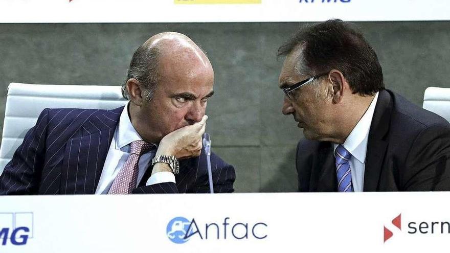 Luis de Guindos conversa con el presidente de Anfac, Antonio Cobo (Opel España), en Madrid. // Efe