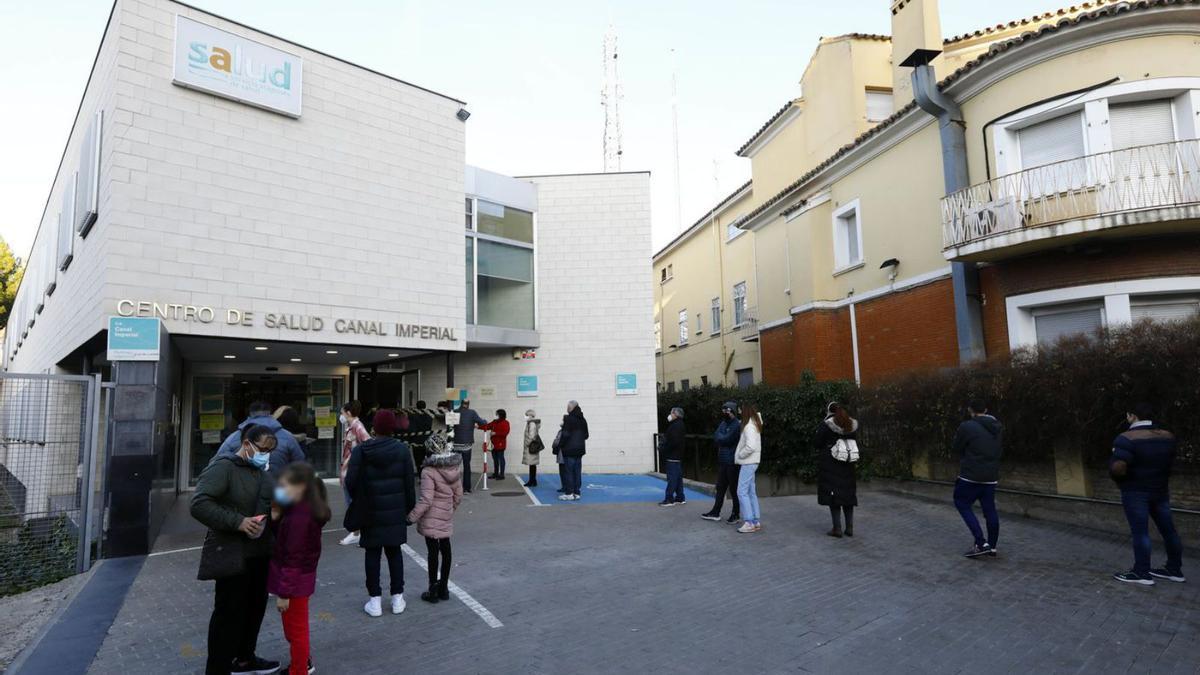 Varias personas hacen fila a las puertas del centro de salud Canal Imperial, en Zaragoza.