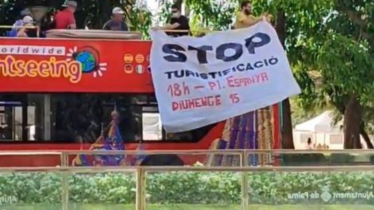 Los activistas de Menys turisme, Més Vida han colocado una pancarta en un autobús turístico, en Palma, para animar a ir a la manifestación de mañana domingo.