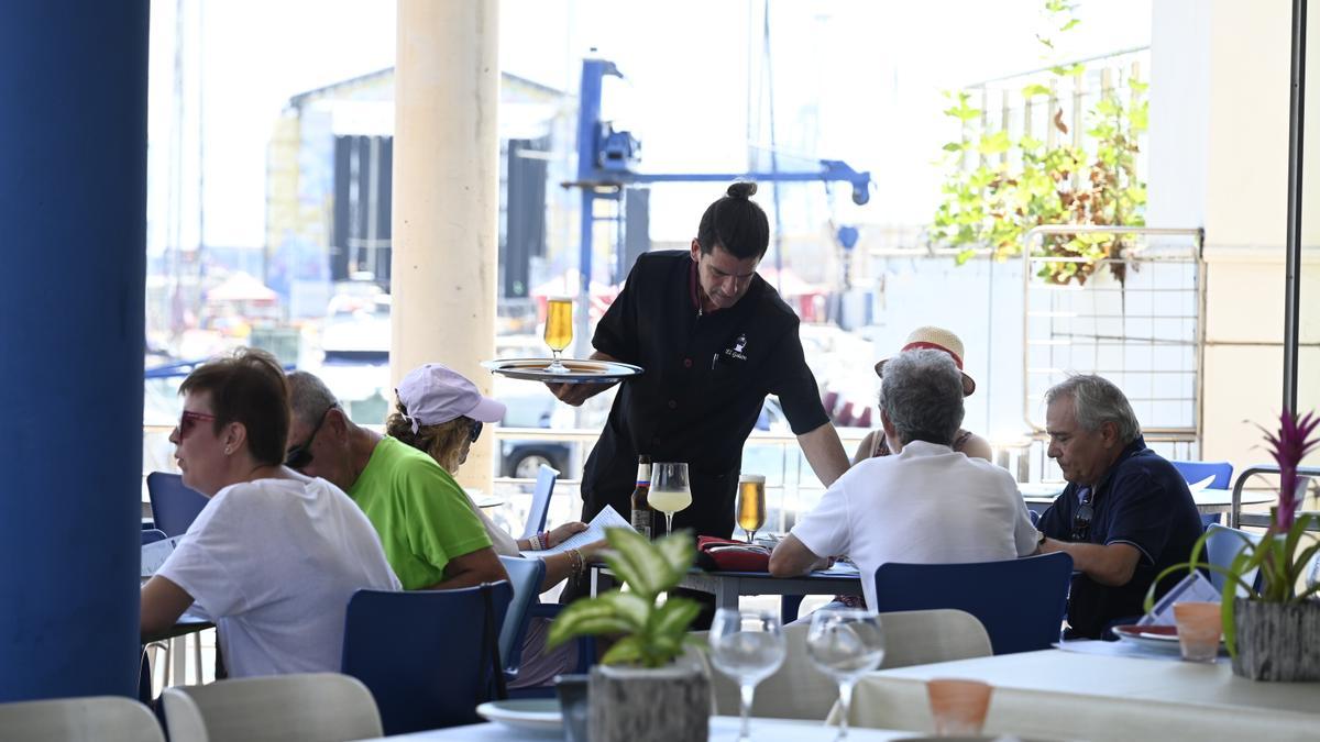 Un camarero sirve mesas en un restaurante de la plaza del Mar del Grau.
