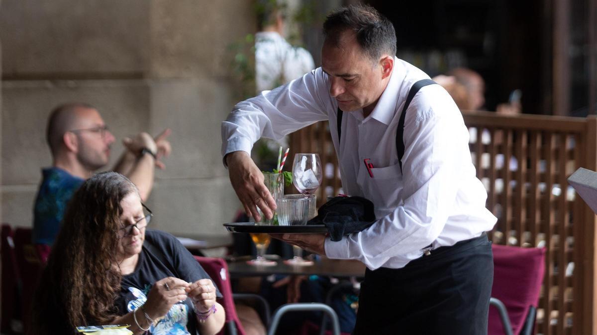 Un camarero atiende a una clienta en un bar.