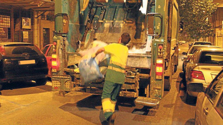 Uno de los empleados de la empresa Urbaser recoge la basura en una calle de Elche.