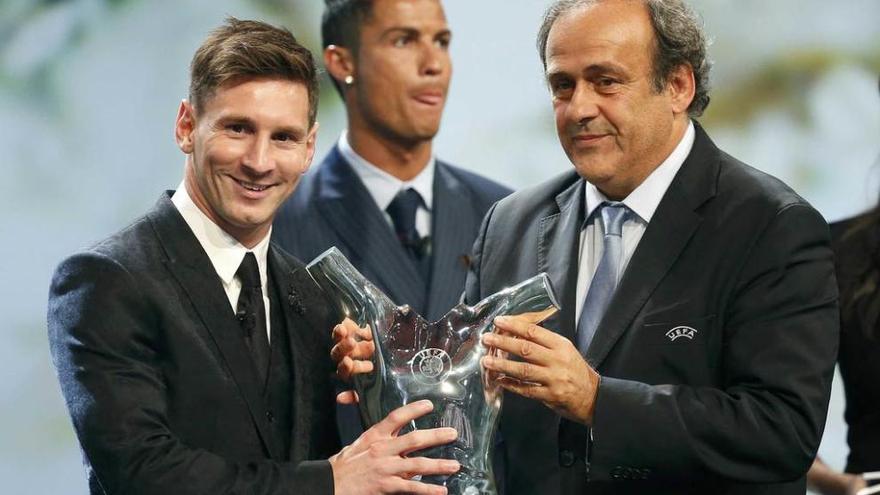 Messi recibe el trofeo de manos de Platini mientras Cristiano Ronaldo mira para otro lado.