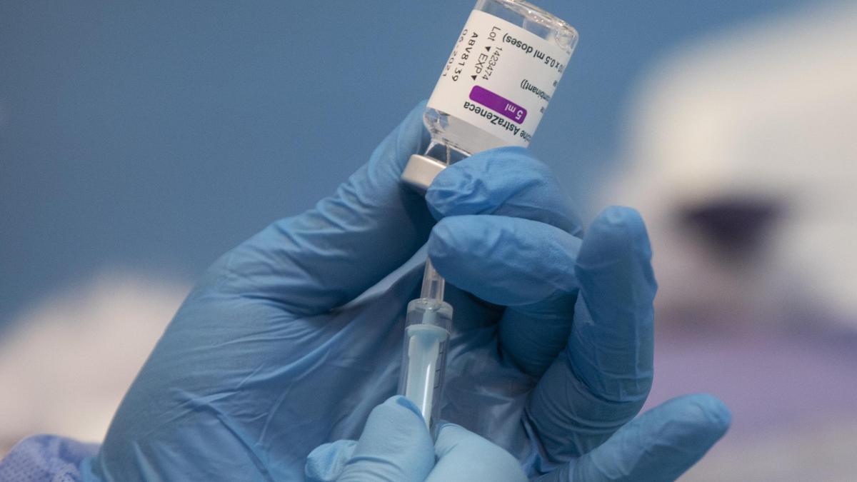 Una profesional sanitaria sostiene una jeringuilla con un vial de la vacuna contra la COVID-19 de AstraZeneca