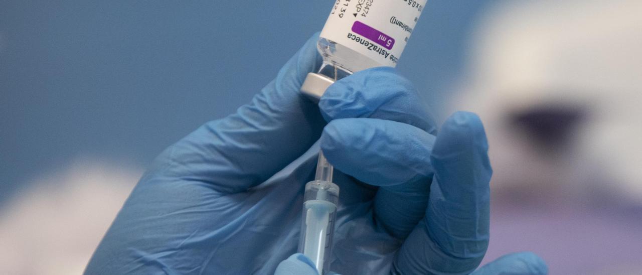 Una profesional sanitaria sostiene una jeringuilla con un vial de la vacuna contra la COVID-19 de AstraZeneca.