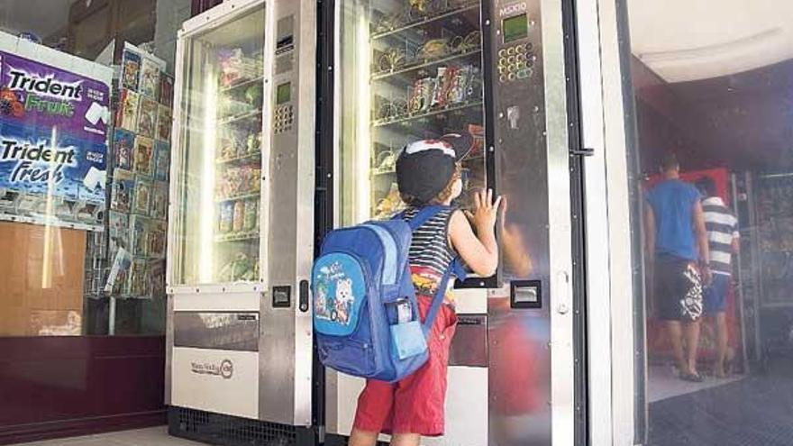 Un niño mira una máquina expendedora con refrescos y dulces. // Eli Regueira