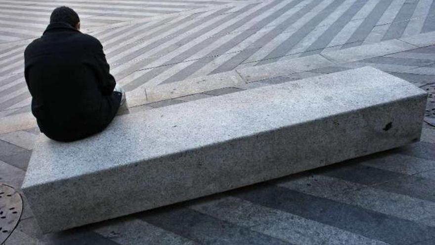 Un hombre sentado solo en la esquina de un banco. / reuters